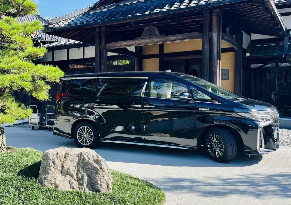 Black Toyota Alphard Hybrid parked at a traditional Japanese entrance